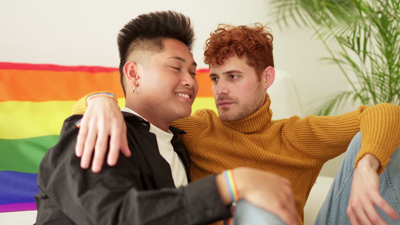 Gay couple embracing in front of a pride flag