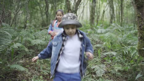 Ethnic-children-with-paper-guide-and-binoculars-exploring-forest