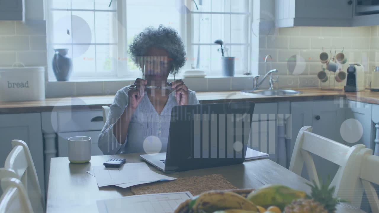 Animation of financial data processing over senior african american woman using laptop