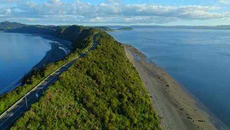 coastal road curving along lemuy island's shore with fishing nets, chiloe, aerial view