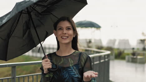 pretty lady with umbrella holds hand under rain drops