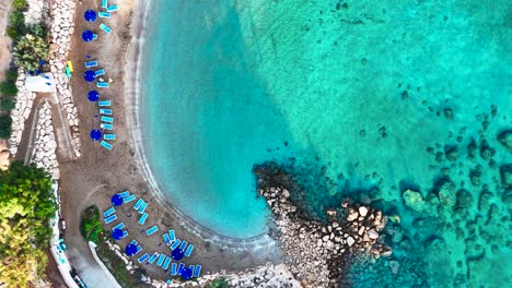 aerial top down view of deck chair line near turquoise water beach, cyprus
