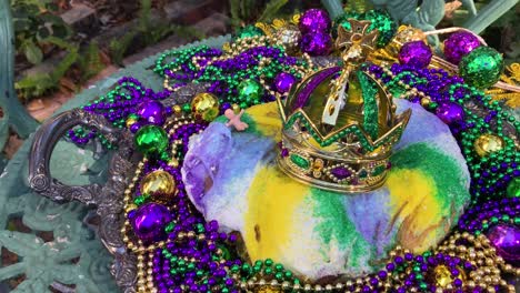 pastel de mardi gras al aire libre con corona y un pequeño bebé rodeado de cuentas coloridas