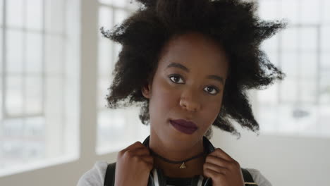 portrait of confident african american woman looking serious at camera young female student with funky afro hairstyle in apartment background
