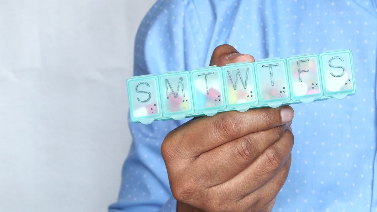 Person holding a weekly pill organizer