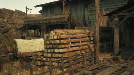 a western town with a wooden shack, a covered wagon and a pile of wood