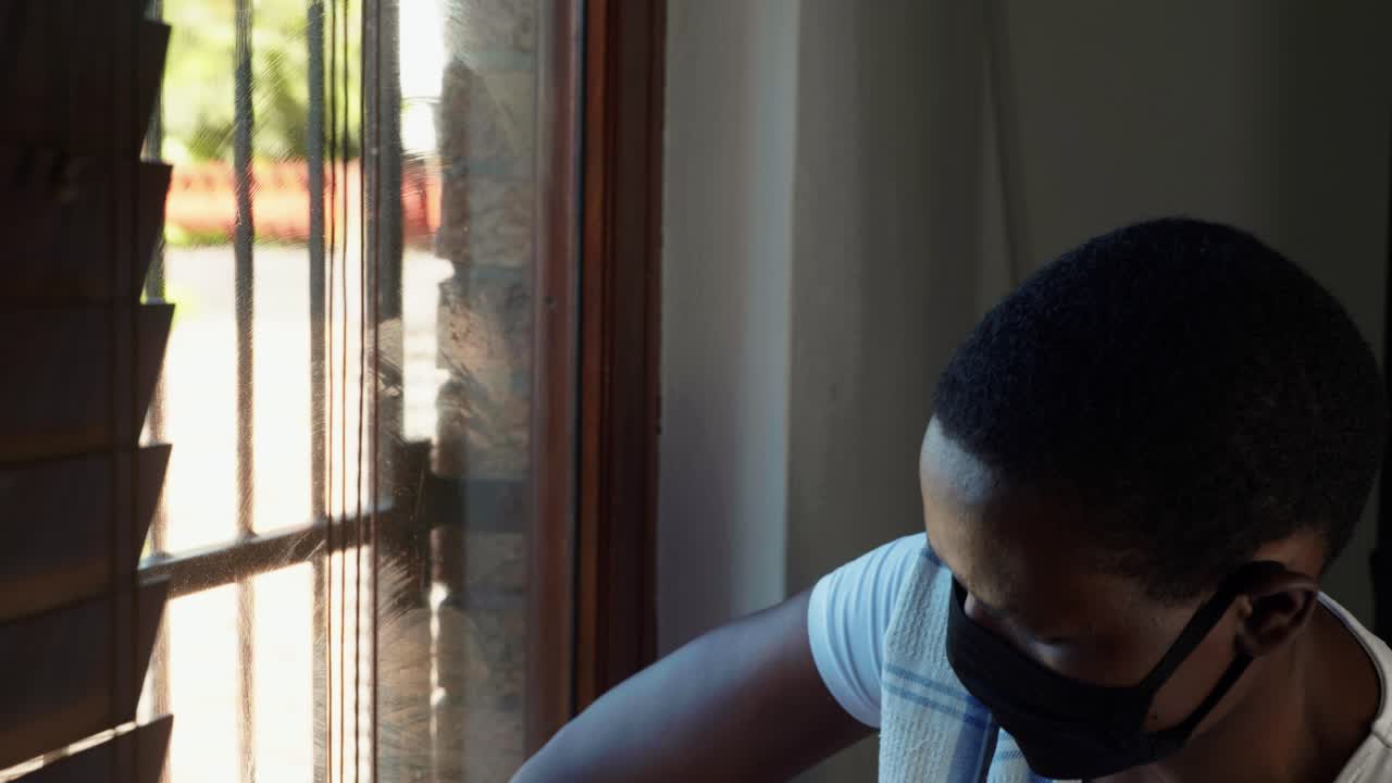 African lady cleaning-disinfect glass window wearing mask and cloves for Covid