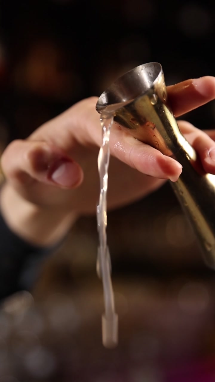 Barman che versa liquido misurato da un jigger