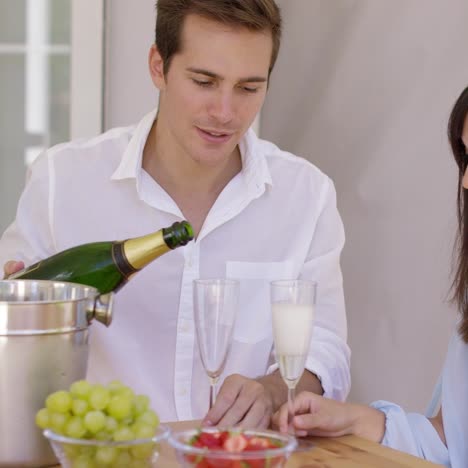 Smiling-young-couple-pouring-champagne-to-drink