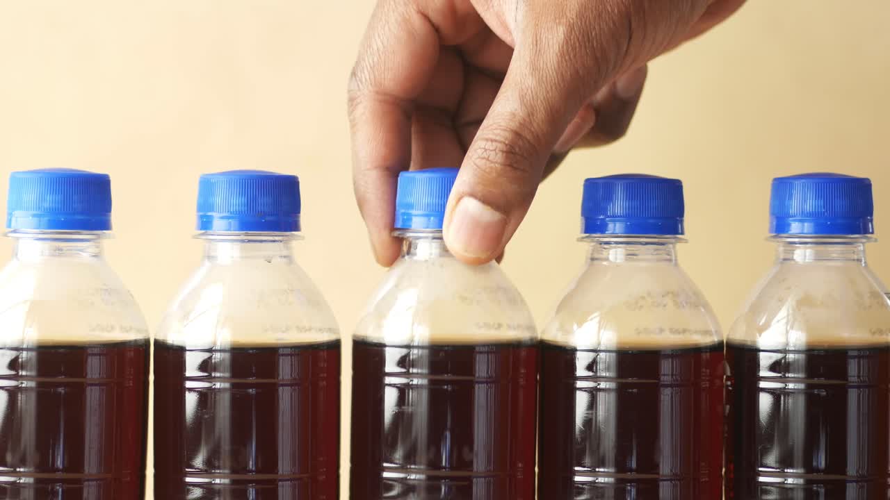 Close-up of Five Bottles of Brown Soda with Blue Lids