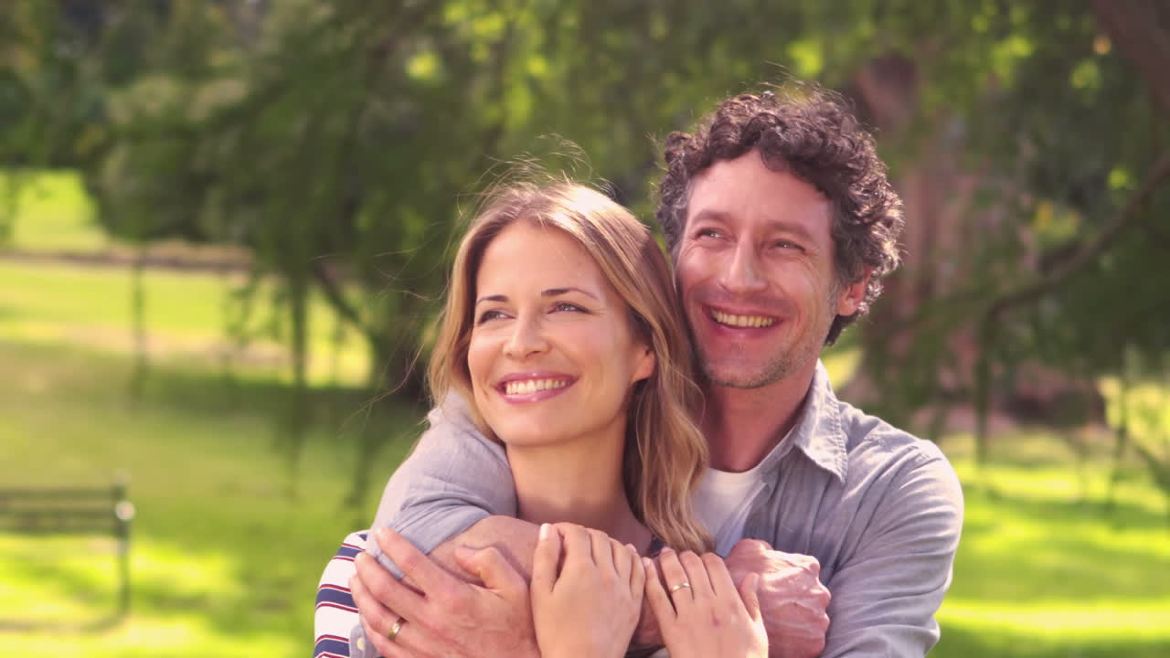 Casal sorridente, abraçando no parque