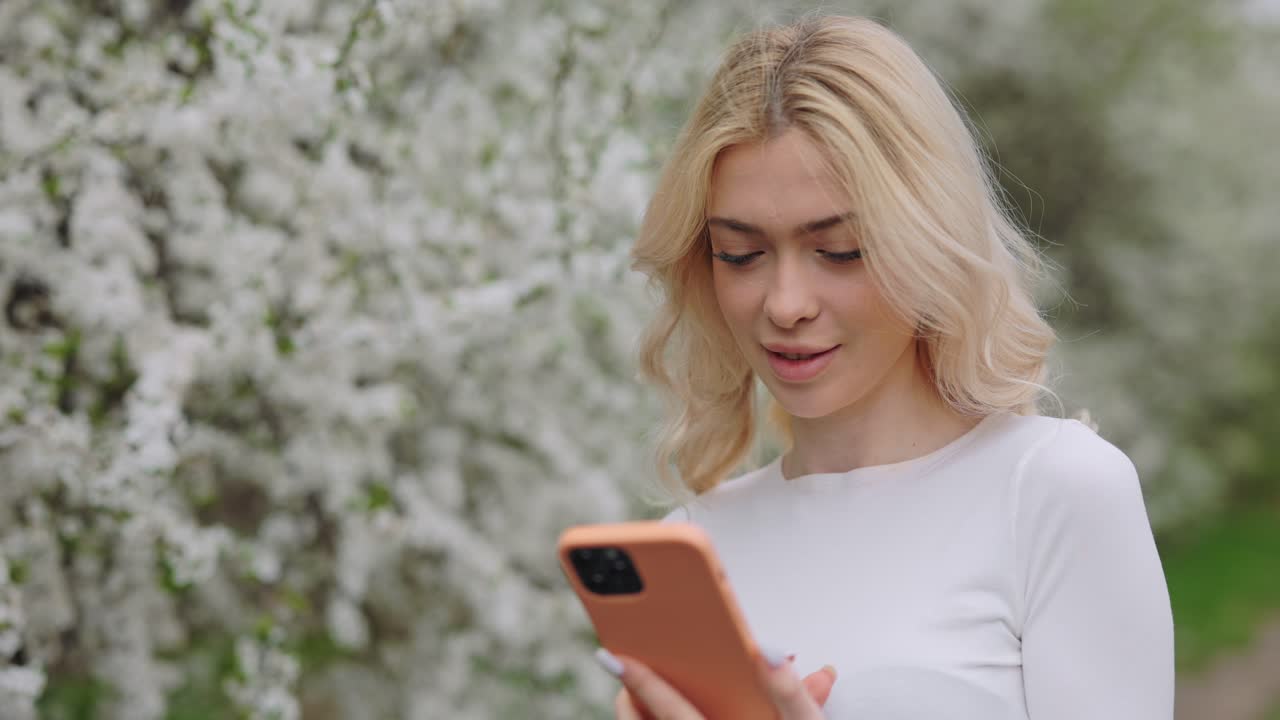 Donna che usa il telefono in un giardino primaverile
