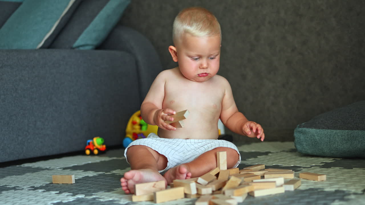 A little boy is playing on the floor at home. The child plays alone at home. Child development