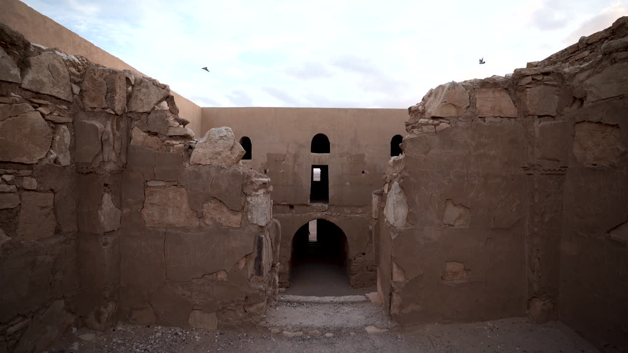 segundo piso del castillo del desierto de qasr kharana con dos pájaros volando uno hacia el otro al otro lado del interior de csatle