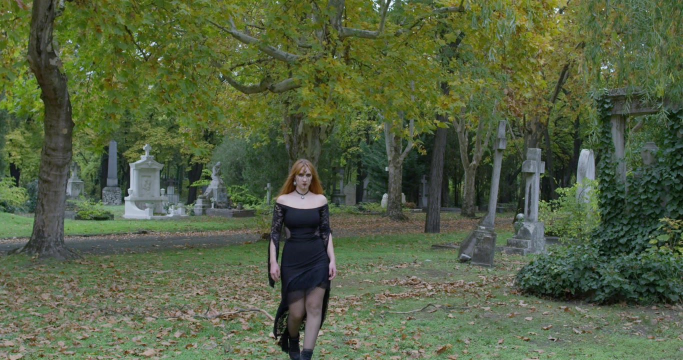Bella strega che sorride in modo malvagio alla telecamera e si gira nel cimitero, rallentatore Primo piano.