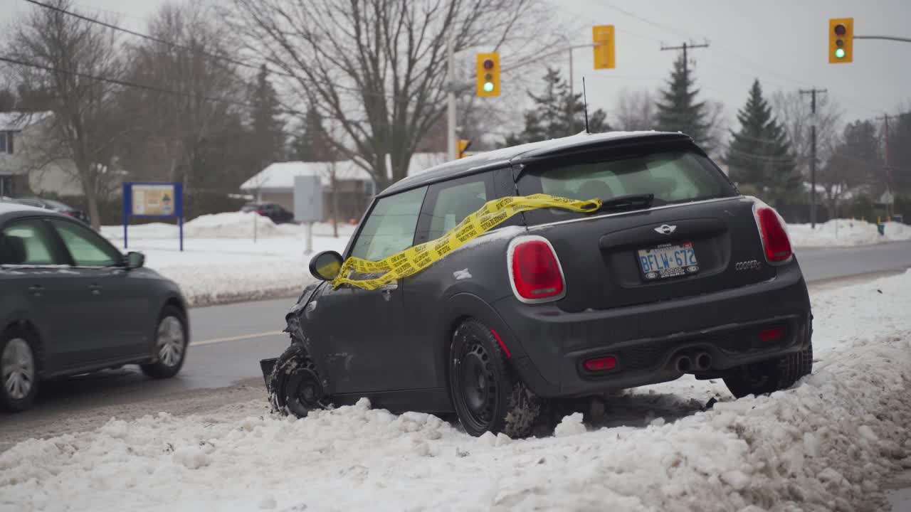 Damaged vehicle in snowbank after accident with police tape attached to it