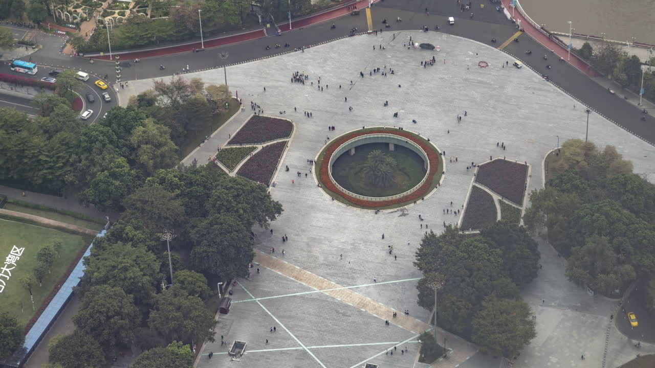 Vista aérea de una concurrida plaza urbana con gente caminando y tráfico.