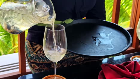 a waiter serves iced drink in bali, conveying a sense of leisure outdoors