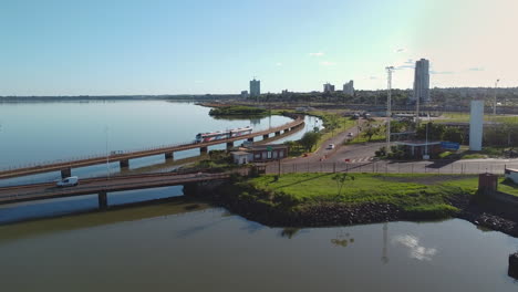 Ein-Stadtbild-Mit-Einem-Zug,-Der-Den-Rio-Parana-Fluss-überquert,-Puente-Internacional-Posadas---Encarnación-Und-Auf-Der-Brücke-Fahrenden-Autos