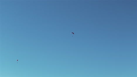 Paragliders-gracefully-float-in-the-air-on-a-beautiful-day-with-a-clear-blue-sky