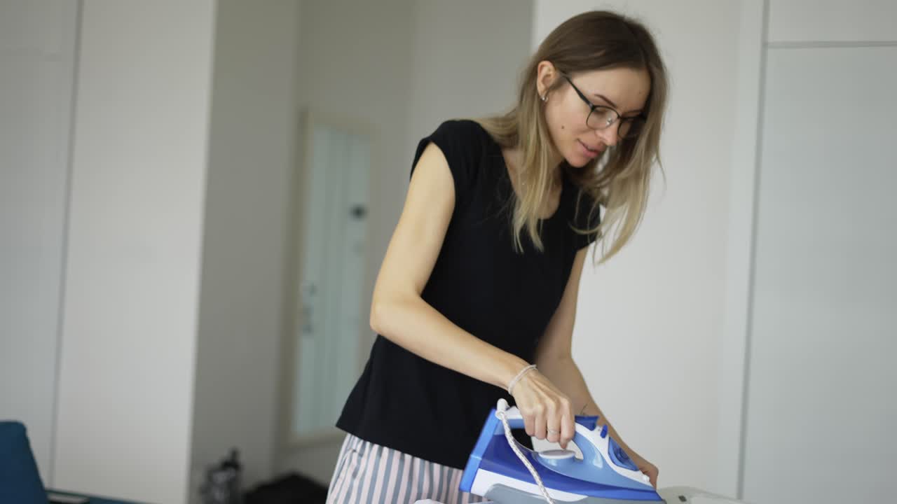 mujer planchando ropa en casa a bordo de buen humor, bailando