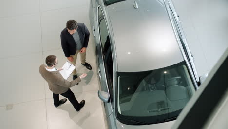 car salesman discussing car details with customer in showroom