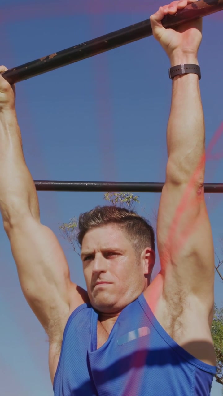 Vertical video: Man gripping pull-up bar doing repeated leg raises for fitness with red dots