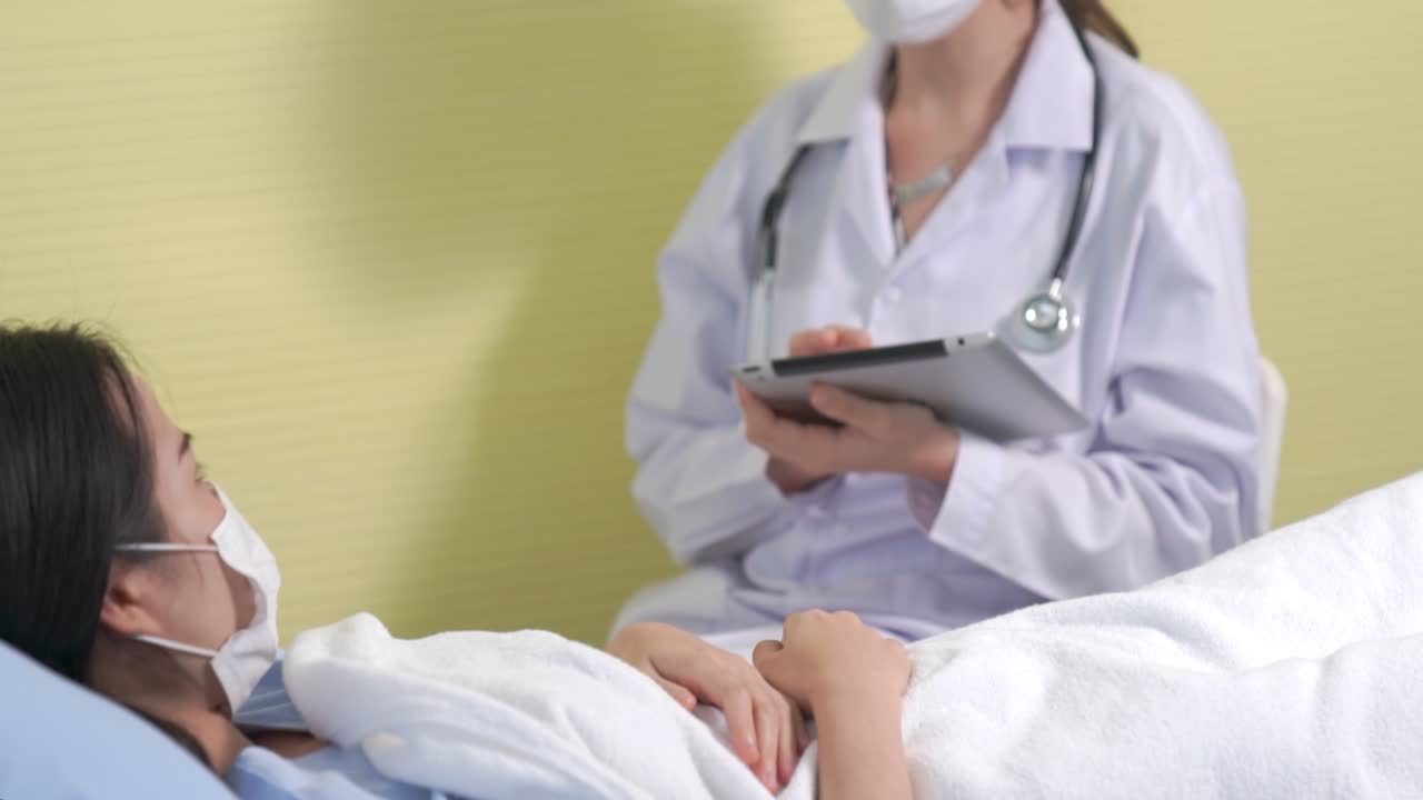 マスクを着用した医師が病棟で患者と丁寧に話す