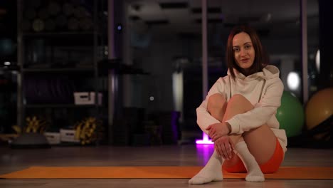 woman sitting on yoga mat in gym