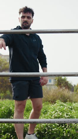 man trains upper body on the bars in the park