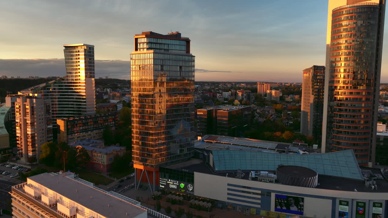 Aerial evening forward flying shot of new urban area with tall shiny glass buildings in Vilnius, Lithuania.Constitution prospectus with city traffic are visible. High quality 4k prores footage.