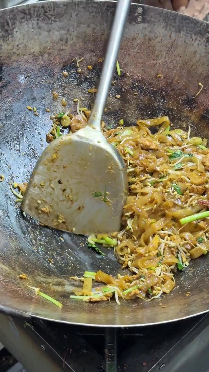 Chef che salta i noodles Pad Thai in un wok