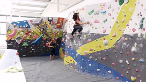 Frauen-Klettern-Boulderwand-Mit-Bunten-Griffen