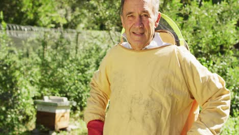 Portrait-of-smiling-caucasian-male-beekeeper-in-protective-clothing