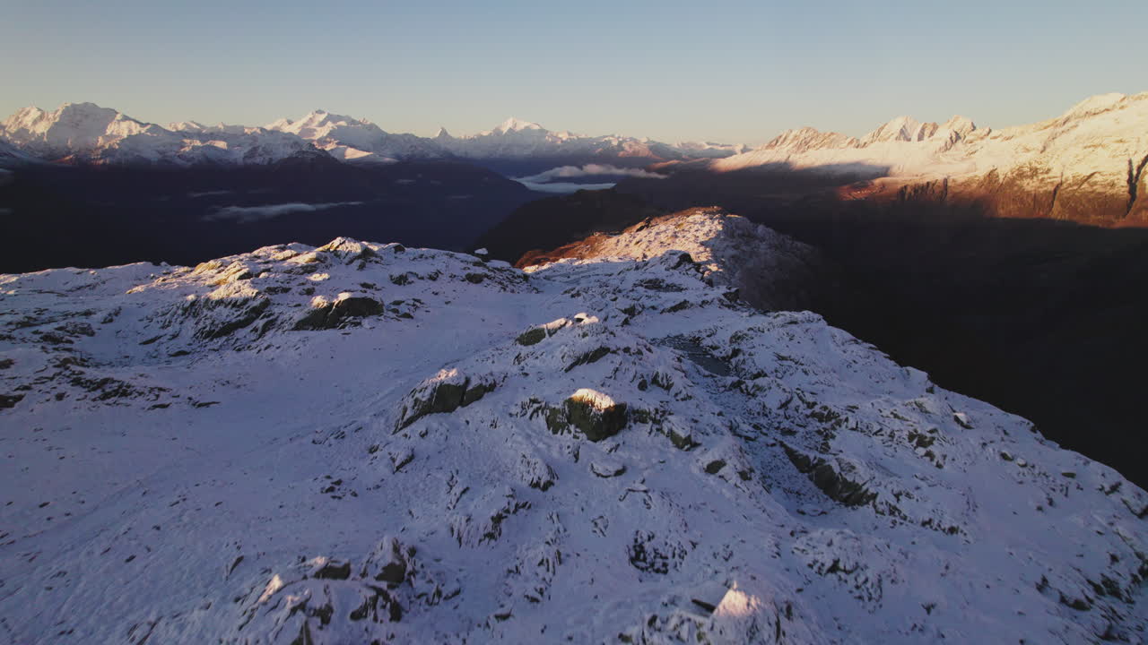 vista aérea de un turista en la cumbre del glaciar aletsch en los alpes suizos al amanecer, el macizo de monte rosa y la montaña matterhorn en el horizonte
