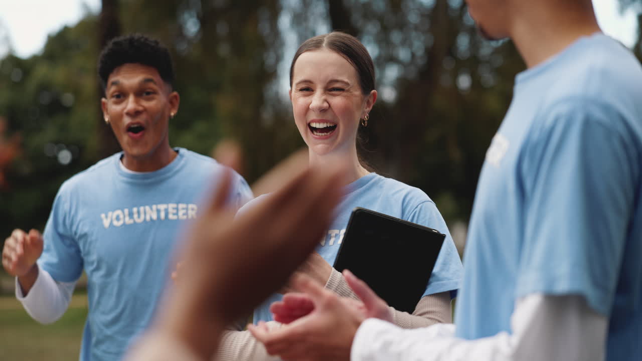 Diverse group of volunteers clapping and smiling together in a park