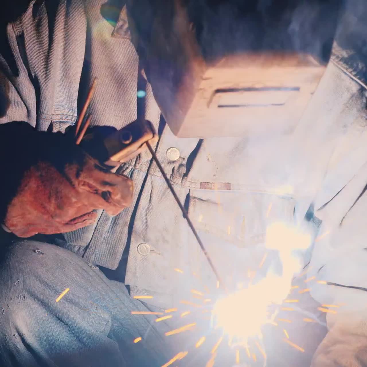 A welder in a protective helmet and clothes welds as sparks fly 6
