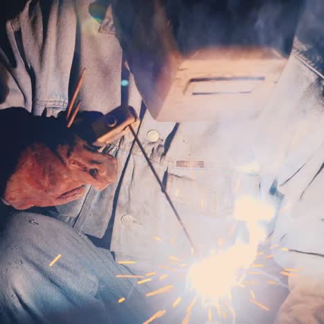 a welder in a protective helmet and clothes welds as sparks fly 6