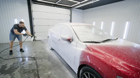 car washing cleaning with foam and high pressured water. red car