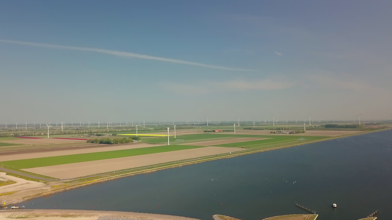 Aerial drone shot of flying forward at the coastline and revealing the flat landscape with wind turbines in the Netherlands.