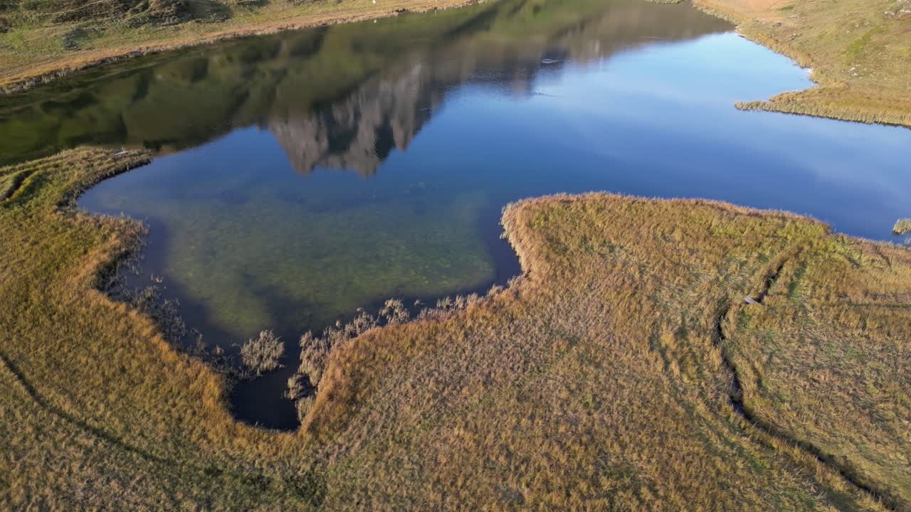 vista aérea de un lago de forma irregular en el prado situado en el valle