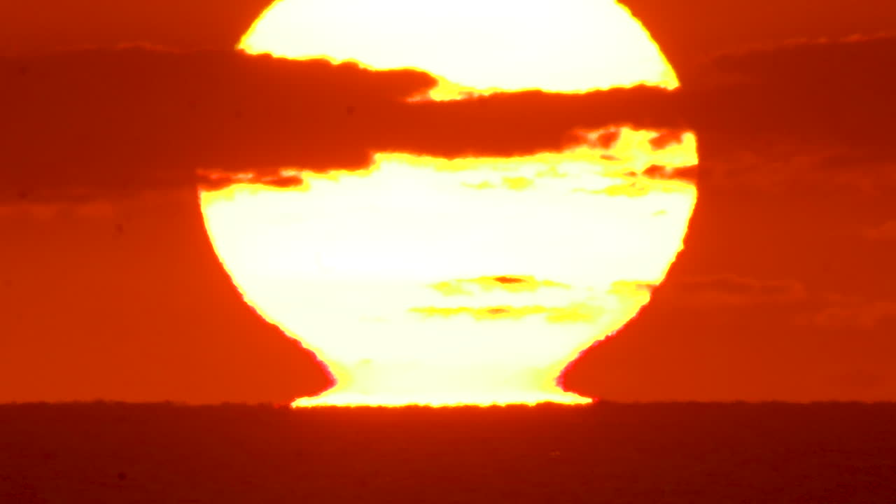 태양이 바다 수평선에서 찢어지면서 일출을 닫고 하늘을 주황색과 분홍색으로 빛나게 합니다.