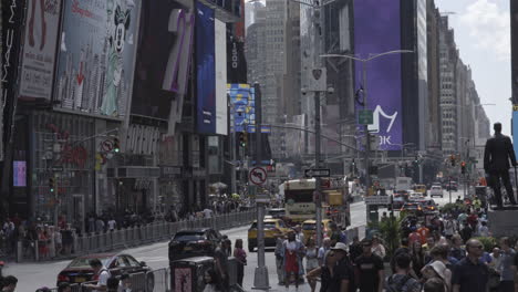 huge commercial signs seen on the tall skyscrapers of new york city with people walking through the busy streets.