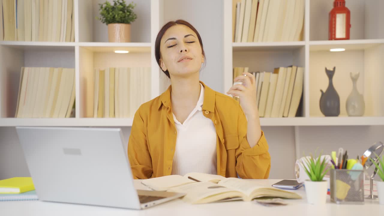una estudiante rociando perfume.