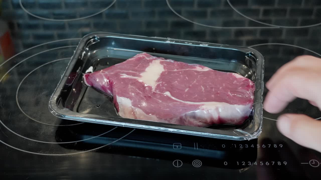 posti di manica negozio comprato in plastica confezionato entrecote manzo su una stufa di superficie di vetro, poi lascia lì