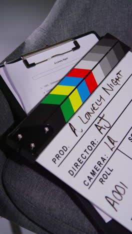 Vertical-Video-Close-Up-Of-Film-Clapperboard-Or-Slate-With-Production-Details-And-Script-Shooting-Movie-Or-Video-In-Studio-2