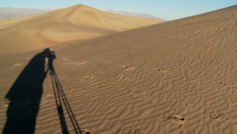 La-Sombra-De-Un-Cineasta-Con-Un-Trípode-En-La-Sombra-Filmando-En-El-Valle-De-La-Muerte-Contra-Las-Vastas-Y-áridas-Dunas