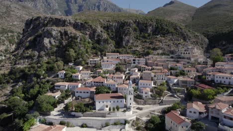 video de drone pasando por el pueblo de nje muaj, spile, sen en himare, en la costa albanesa, lash8, hasta llegar a las montañas