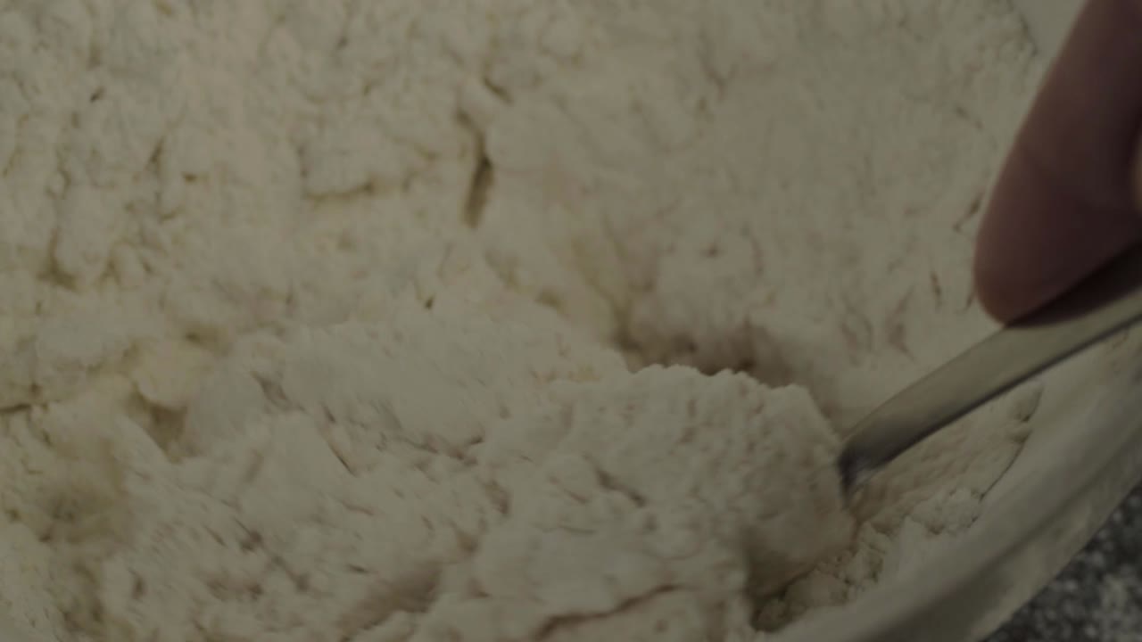 Mixing flour with a spoon in a bowl close up shot