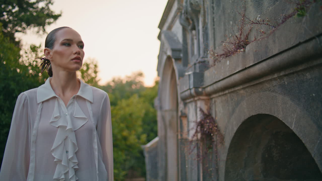 멋진 여행자가 밖에서 고대 건물을 탐험하고 있습니다. 옛 벽에서 는 여자